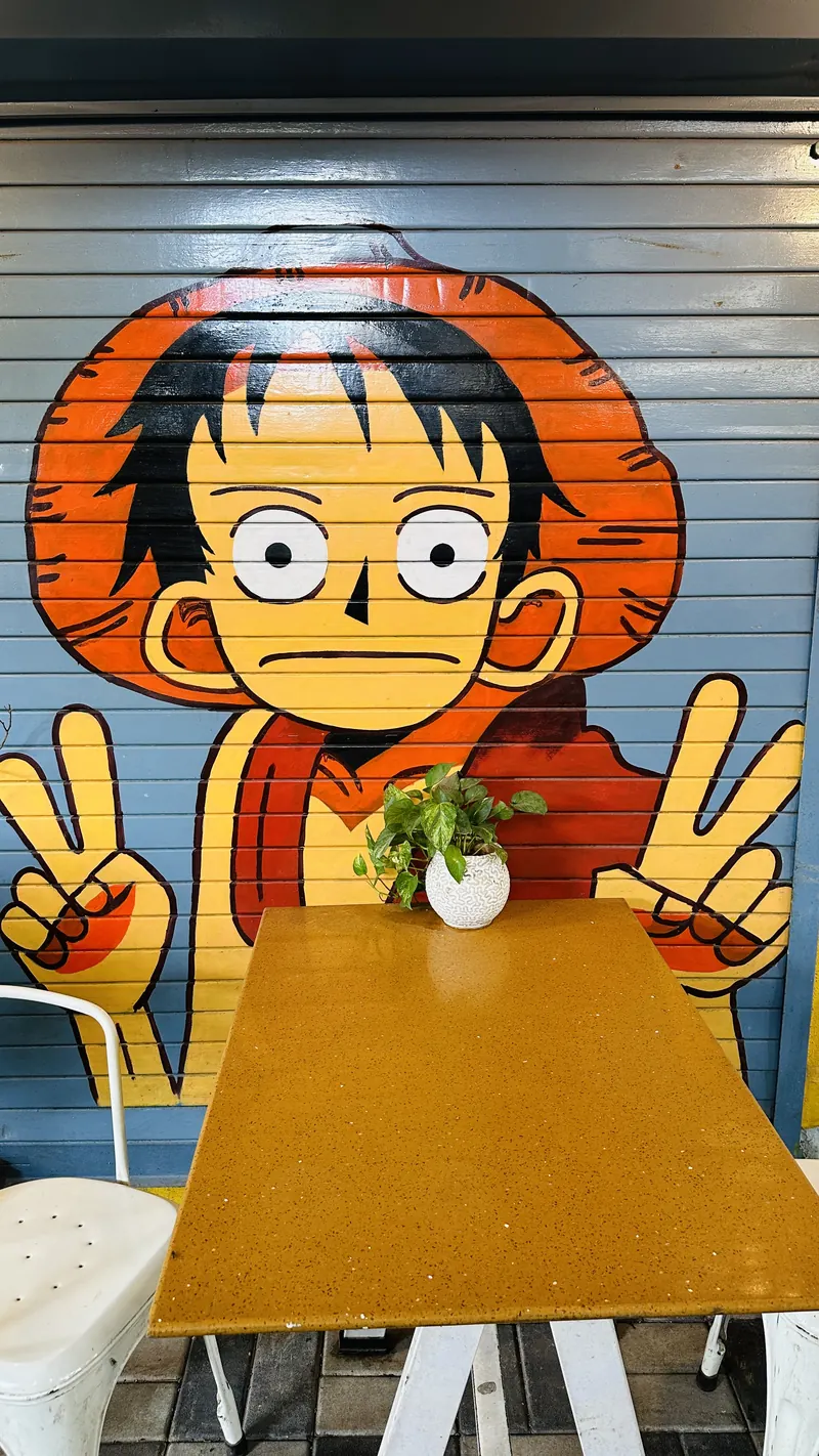 Hand-painted Luffy mural behind a two-seater table