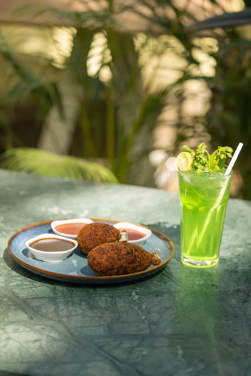 Meat on bone with dips and a mint mojito on a green marble table